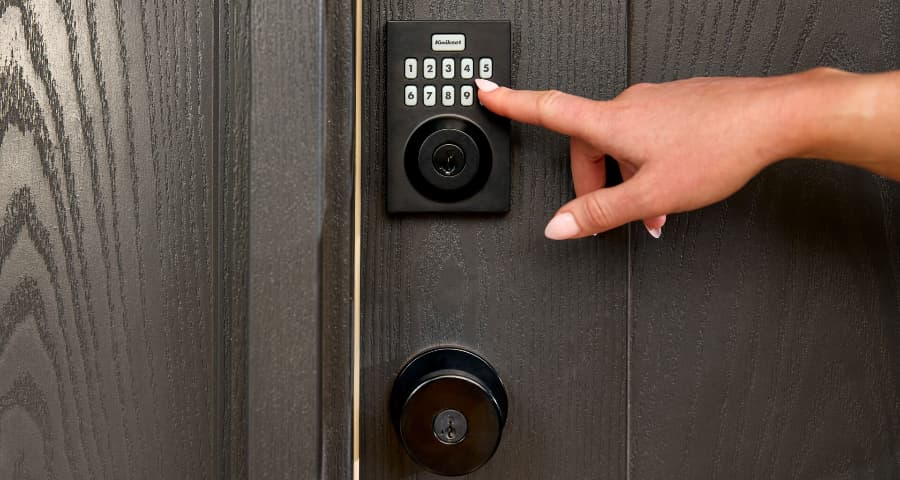 Person pressing the keypad of a Vivint smart lock from Kwikset